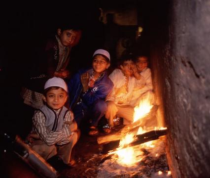 Boys sitting next to a fire in an alley off of a street market in Delhi.