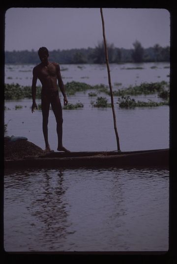 Man standing on his pole-boat at dusk in the backwaters near Fort Cochin, Kerala state.