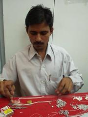Man stringing pearls for Preethi.