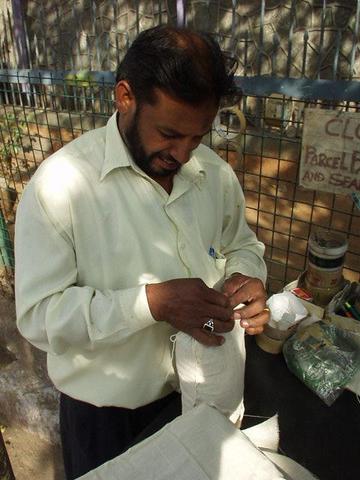 Man sewing up a package, Hyderabad post office.